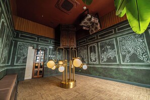 A room with a patterned wall, a wooden cabinet, a door, and a floor lamp.
