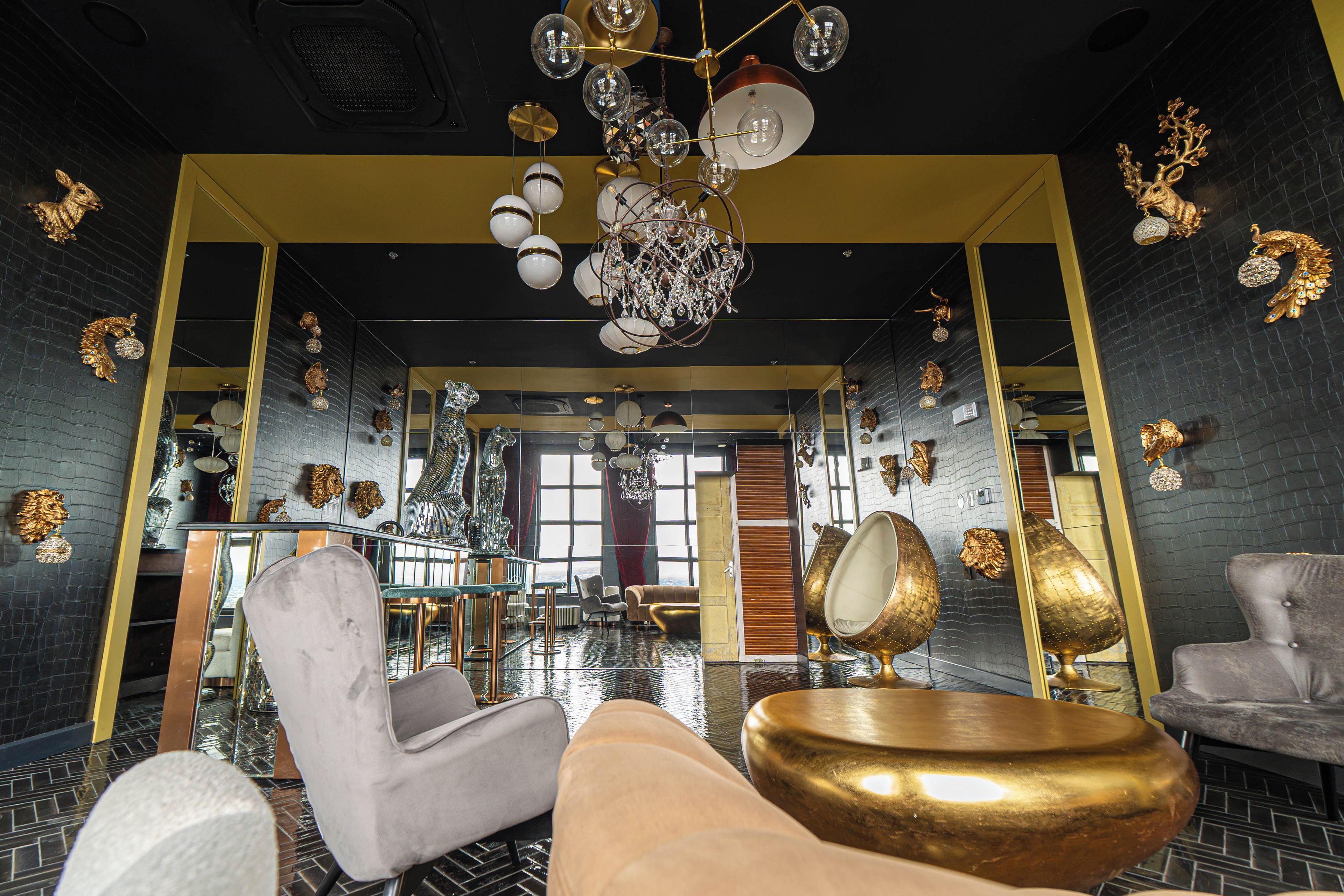 Un interior lujoso con techos altos, candelabros ornamentados y diversas opciones de asiento, incluyendo sillones y sofás.