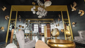 Un interior lujoso con techos altos, candelabros ornamentados y diversas opciones de asiento, incluyendo sillones y sofás.