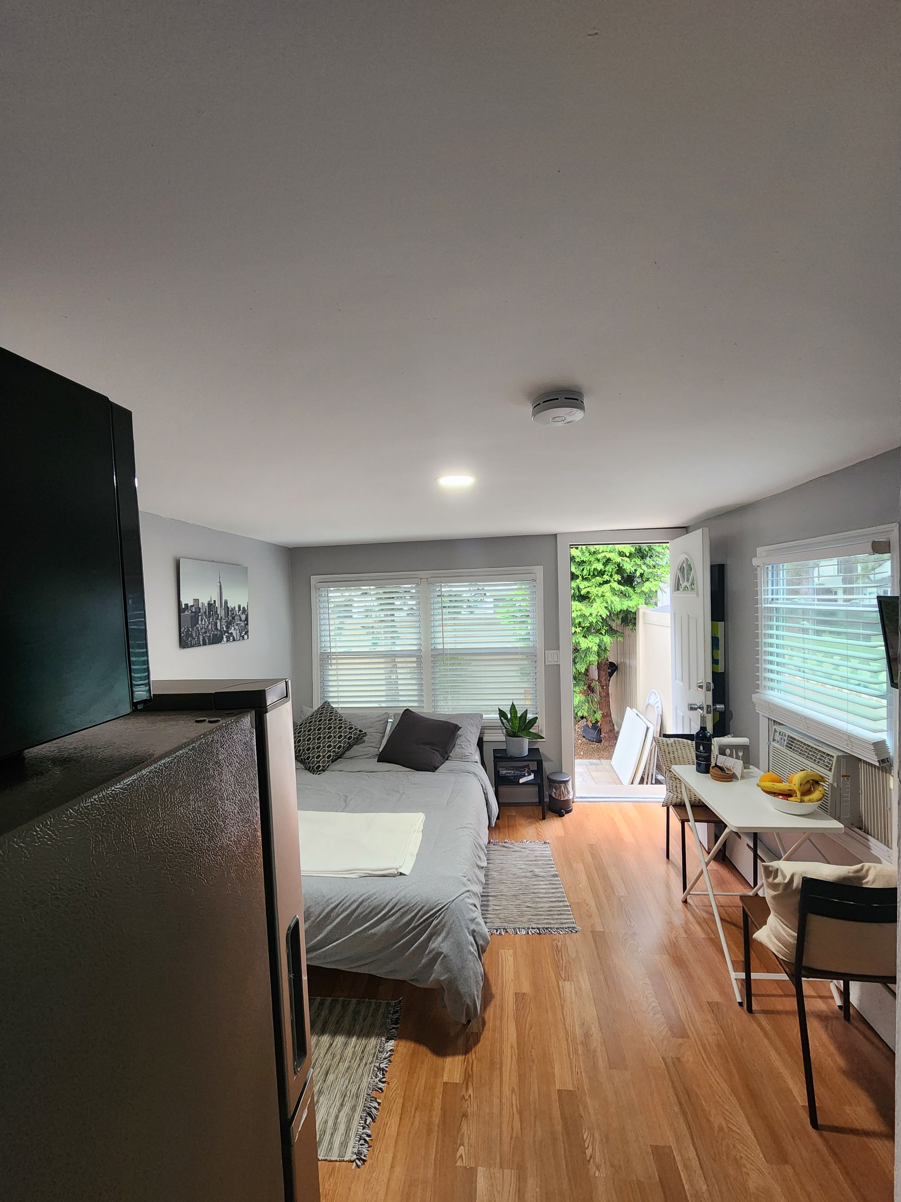 A modern bedroom with a bed, bedside tables, a desk, and a television.