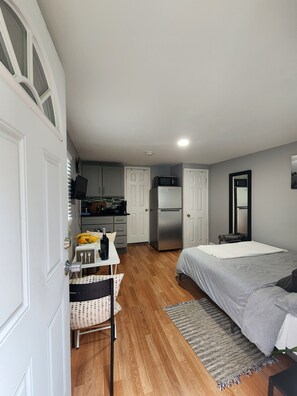 A compact bedroom with a bed, a small table with a bottle, and a chair. - Cozy studio in a lovely Forest Hills neighborhood (Forest Hills)