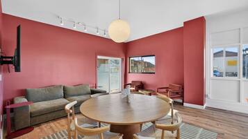 A modern living room with a round wooden table, a sofa, and a television.