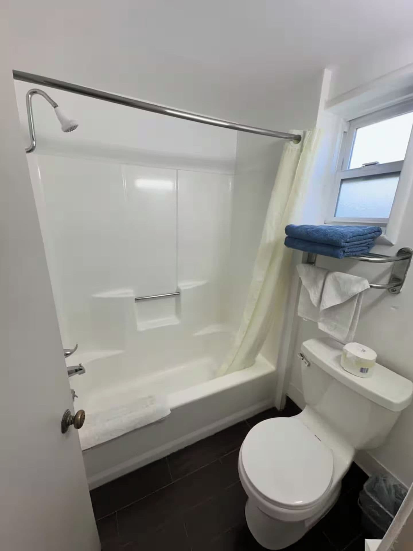 Un baño con ducha de vidrio, inodoro y ventana.