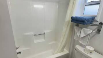 Un baño con ducha de vidrio, inodoro y ventana.