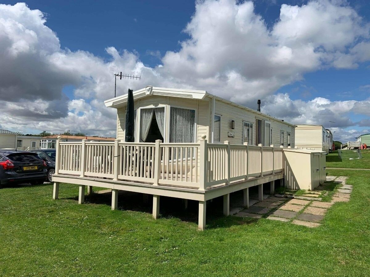 Une maison mobile dotée d’une terrasse, d’une cheminée et d’une antenne parabolique.