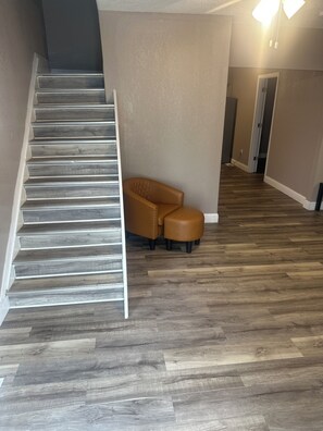 A staircase leading to a landing with a brown leather sofa and ottoman.