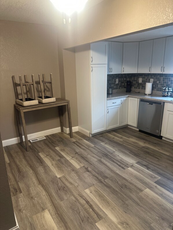 A kitchen with a wooden dining table, white cabinets, and a dishwasher.