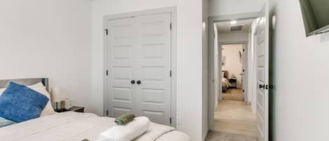 A hotel room with a bed, a ceiling fan, a door, and a TV mounted on the wall.