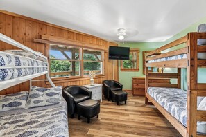 Ein Zimmer mit Etagenbetten, einem Schreibtisch, einem Stuhl und einem Fernseher.