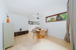 Eine moderne Küche mit Essbereich, Holzboden und Blick auf Grünfläche.