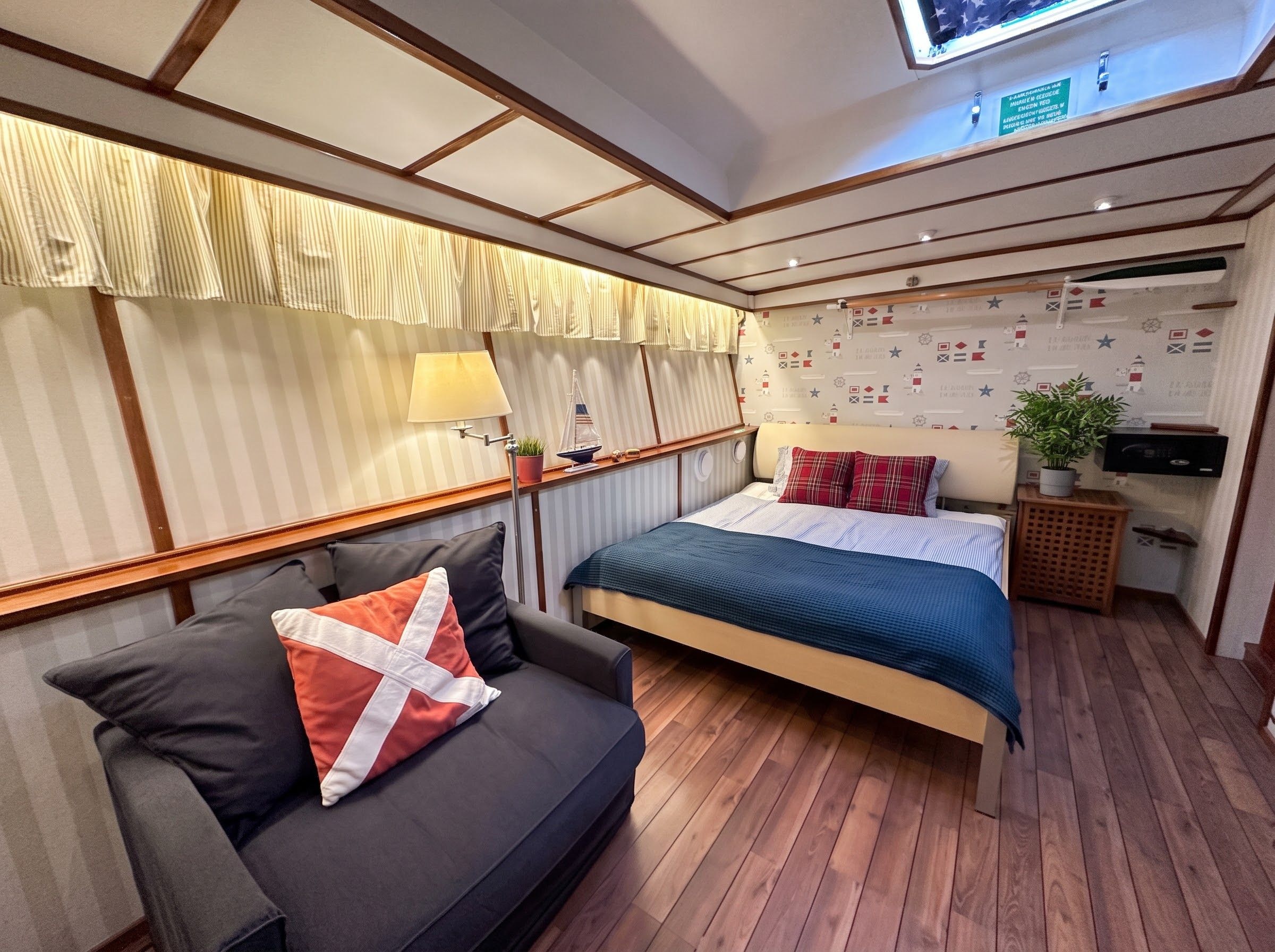 Une chambre à coucher comprenant un lit, un canapé, une petite table, une plante et un mur recouvert d’un papier peint sur le thème de la marine.
