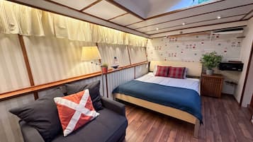 Une chambre à coucher comprenant un lit, un canapé, une petite table, une plante et un mur recouvert d’un papier peint sur le thème de la marine.
