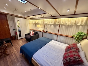 Un dormitorio con una cama, un escritorio, una silla y una planta en maceta.