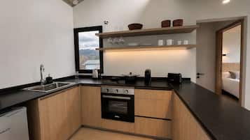 Une cuisine moderne dotée d’un four encastré, d’un évier et d’une fenêtre donnant sur un paysage pittoresque.