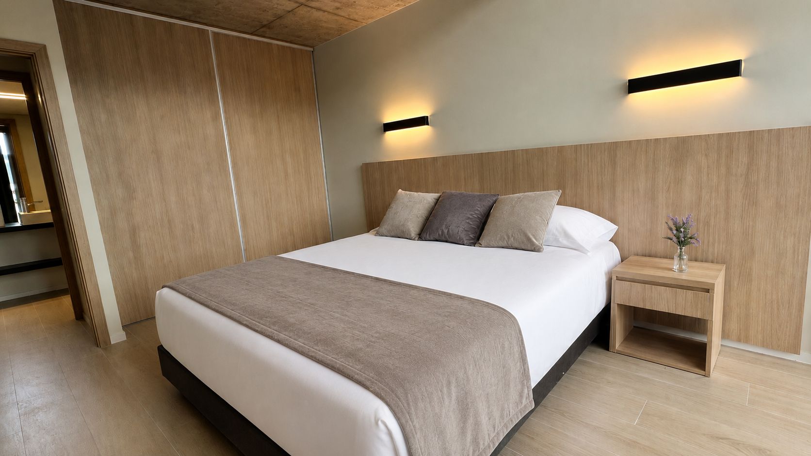 Quarto moderno com cama grande, cabeceira de madeira, mesas de cabeceira e mesa de apoio com um vaso.