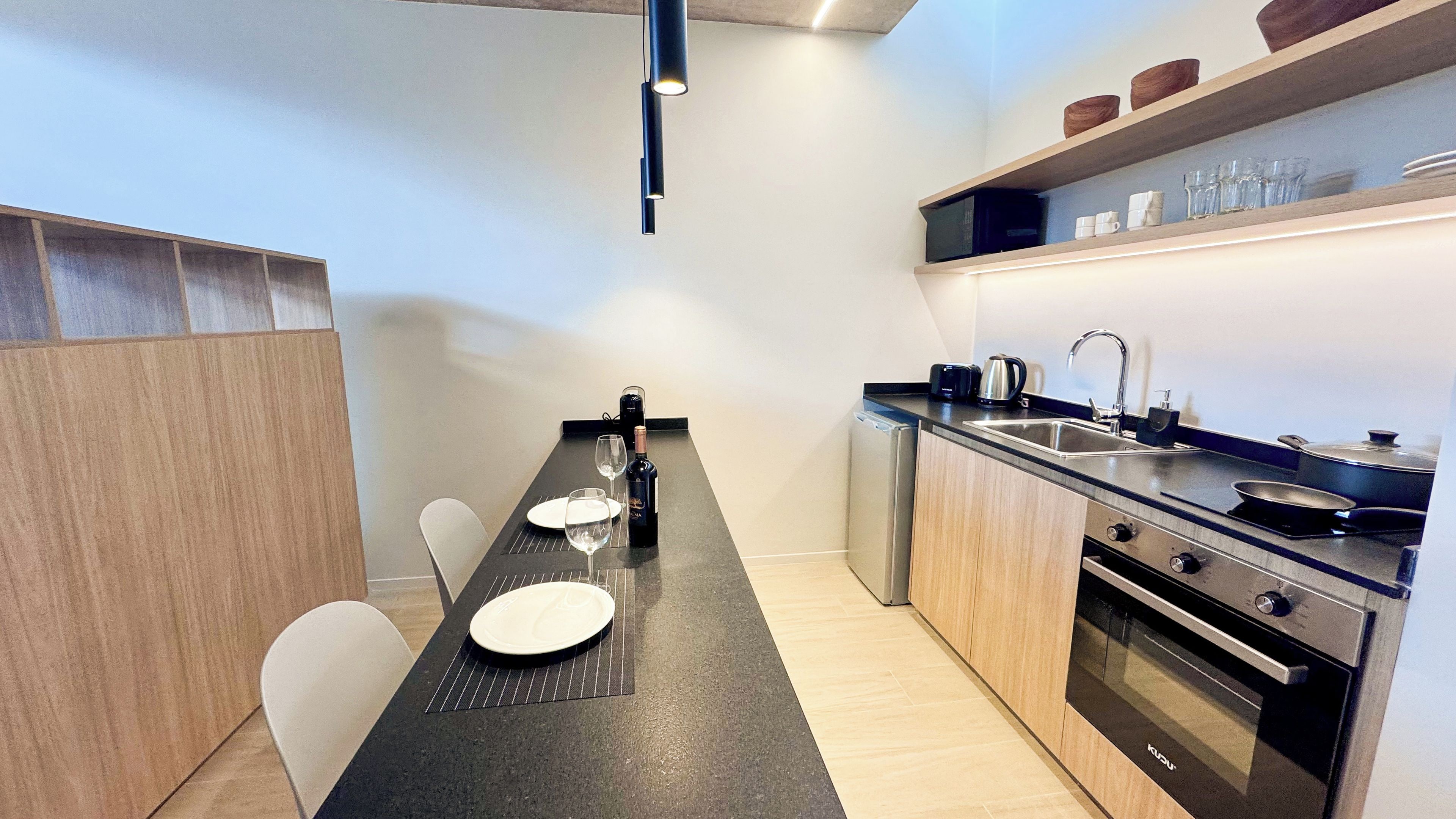 A compact kitchen with a dining area, equipped with modern appliances and a coffee maker.