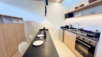 A compact kitchen with a dining area, equipped with modern appliances and a coffee maker.