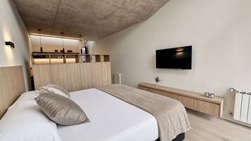 Une chambre à coucher moderne, équipée d’un lit, de tables de chevet, d’un téléviseur et de rangements intégrés.