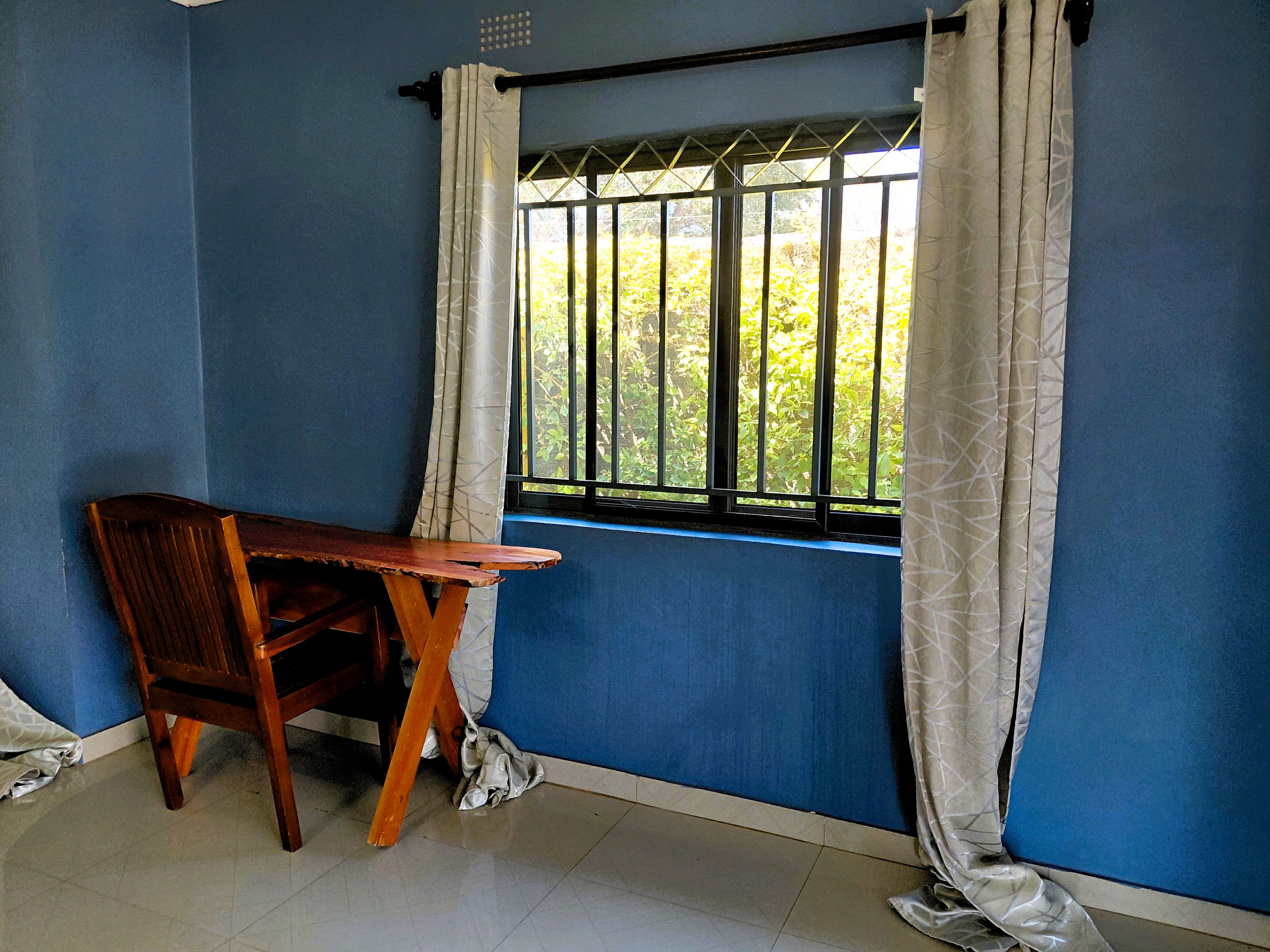 Une pièce avec une fenêtre, un bureau en bois et une chaise.