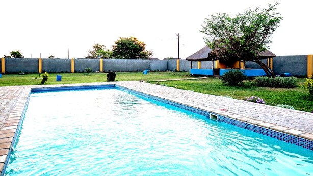 A rectangular swimming pool with a tiled edge, surrounded by a paved walkway. - Charming 3-bedroom house with AC in lively Lusaka (Lusaka)