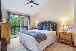 A bedroom with a bed, a ceiling fan, a nightstand with a lamp, and a view of the outdoors. - Timber Falls - Top Floor Views & Steps to Bus (Vail)