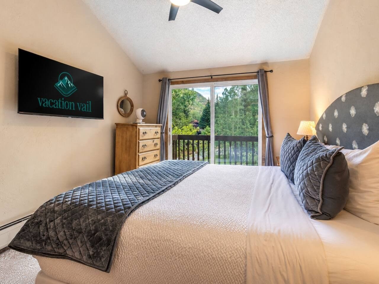 A bedroom with a bed, a nightstand, a television, and a view of a balcony.