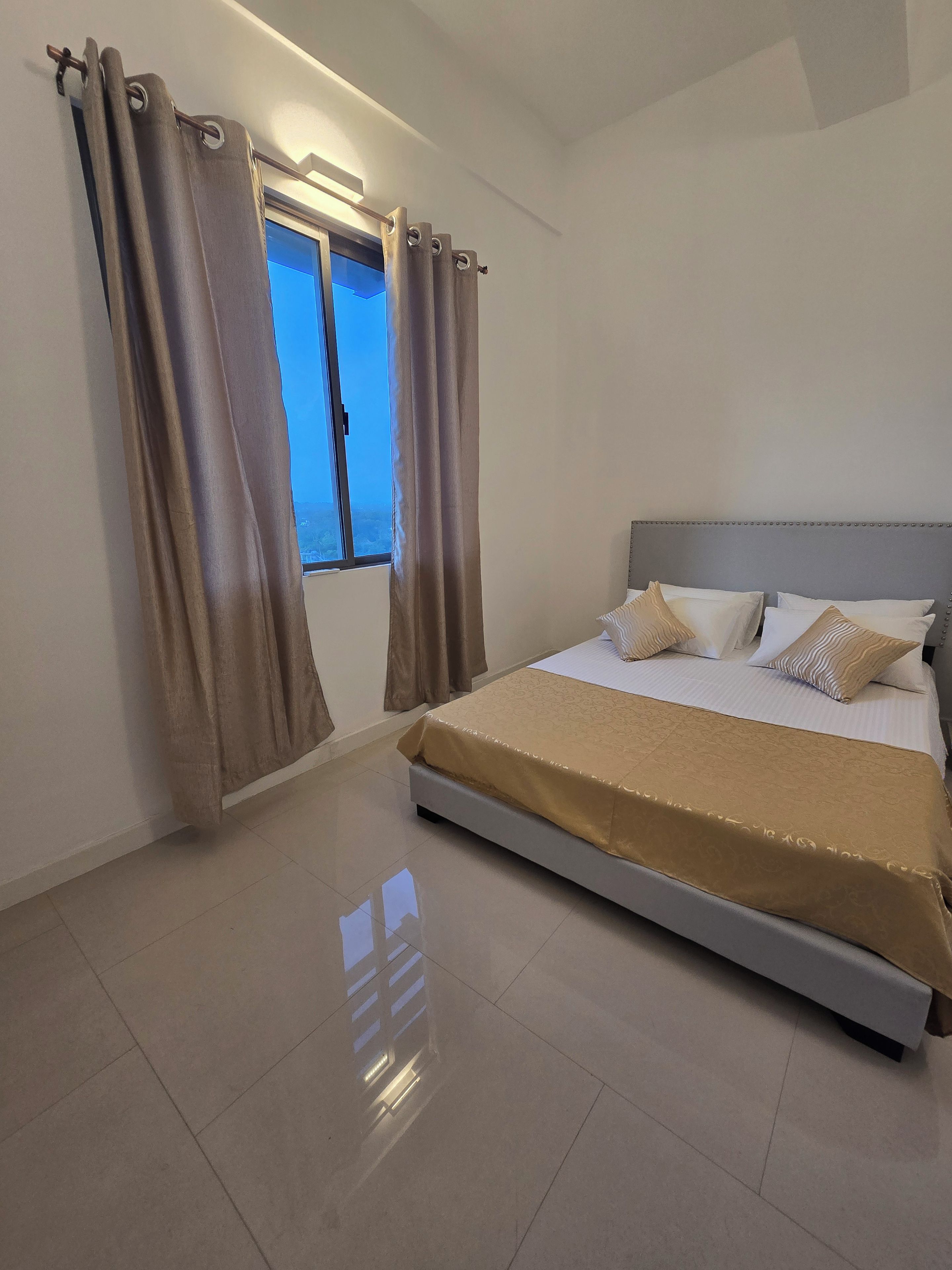 A bedroom with a bed, curtains, and a window.