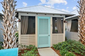A single-story building with a light blue door, beige walls, and a corrugated metal roof. - Steps to The Beach • Resort Pools • Pier Park (Panama City Beach)