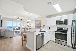 A modern kitchen with white cabinets, stainless steel appliances, and a central island. - Steps to The Beach • Resort Pools • Pier Park (Panama City Beach)