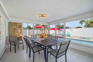 A sunlit patio with a pool, outdoor furniture, and a view of the backyard. - Newly Remodeled w/ Heated Pool! Near Anna Maria! (Bradenton)