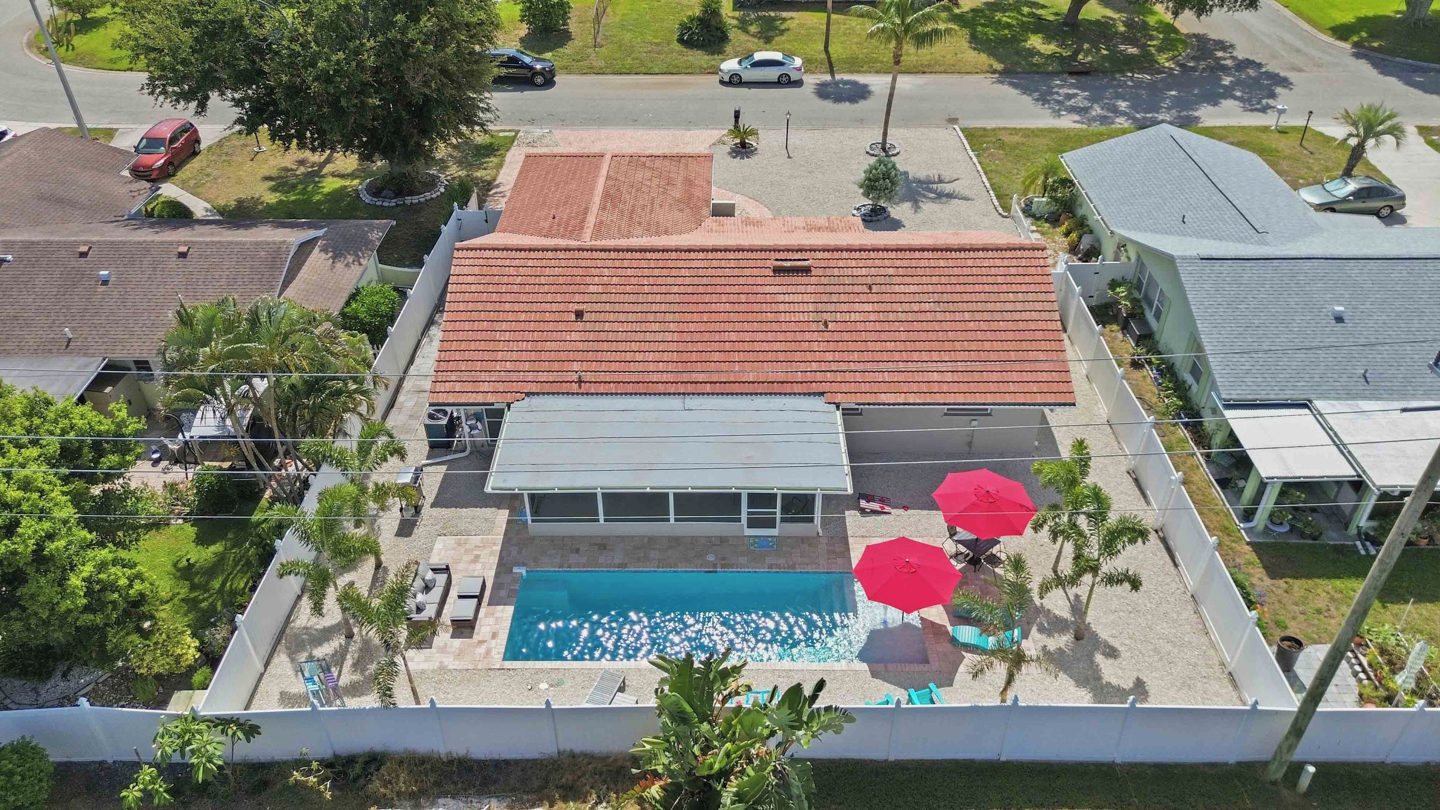 A residential property with a swimming pool, covered patio, and a red-tiled roof.