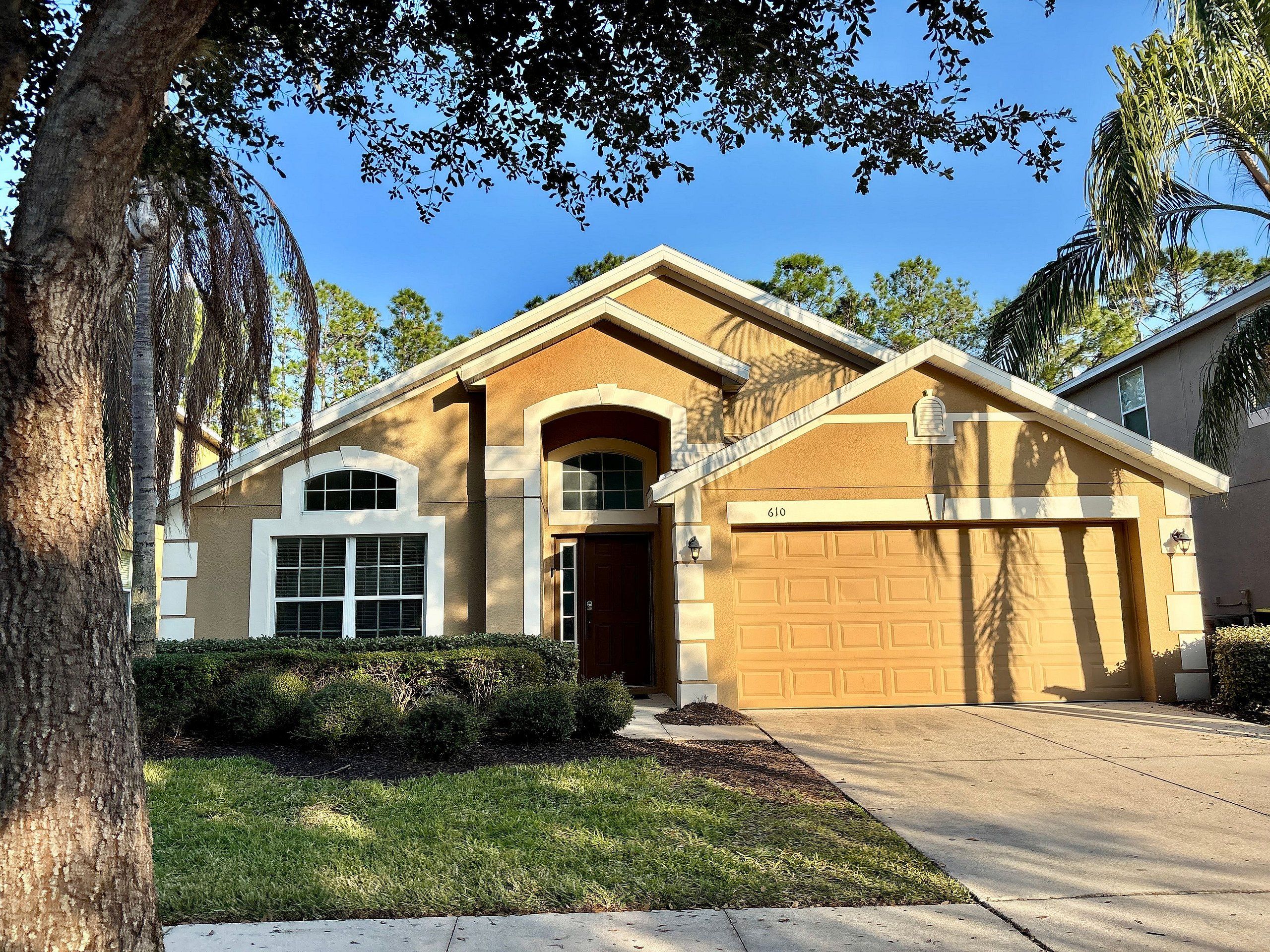 A residential house with a garage, a well-maintained lawn, and mature trees.