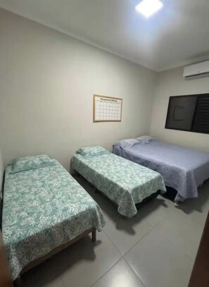 A room with two single beds, a wall calendar, and an air conditioning unit.