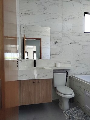 Une salle de bain moderne avec un meuble-lavabo en marbre, des toilettes et une baignoire.