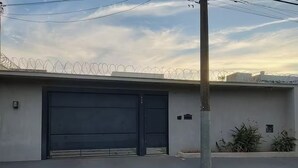 Ein Gebäude mit einer großen Garagentür, einem Zaun mit Stacheldraht und einem Strommast.