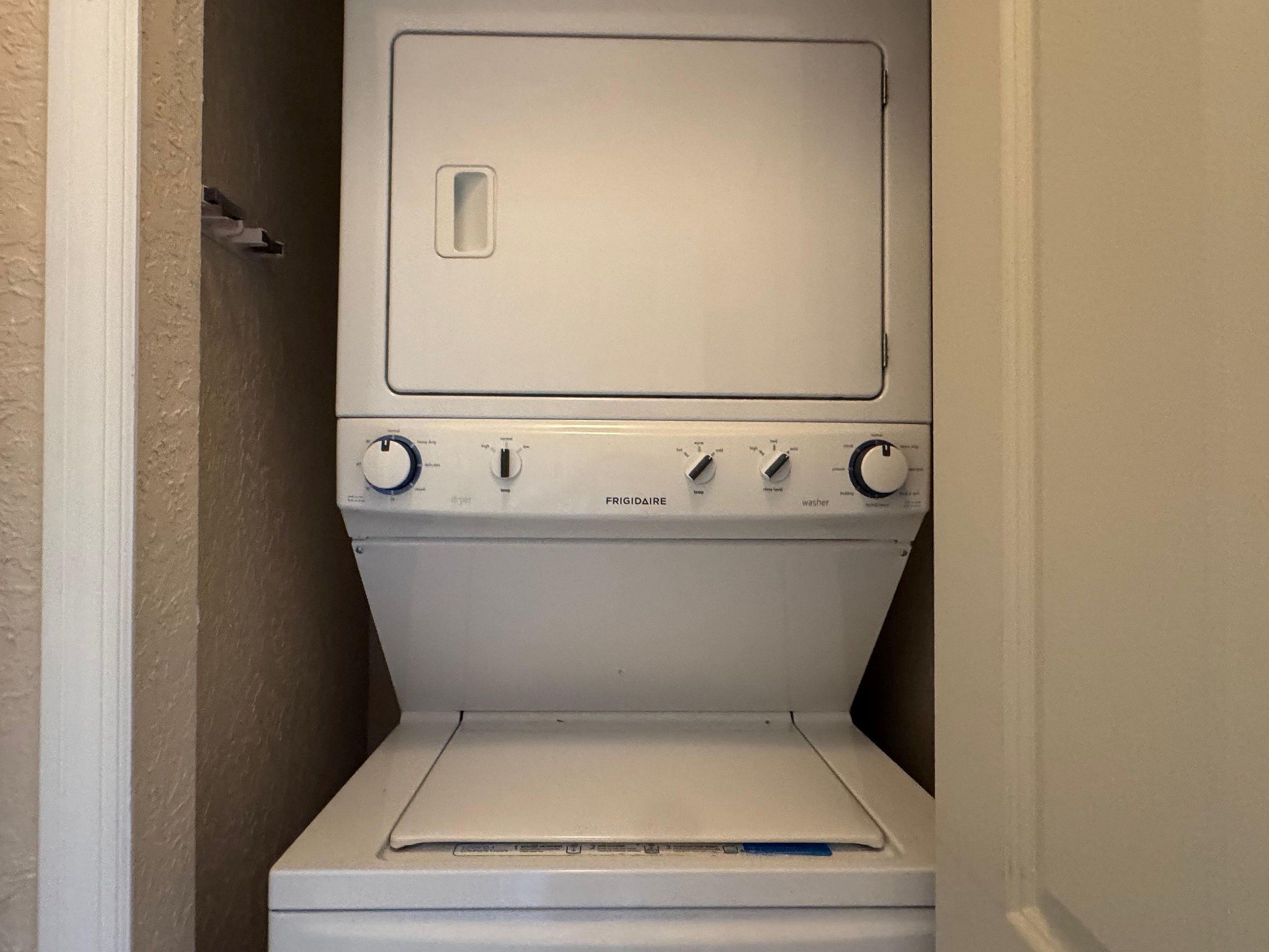 Un appareil combiné lave-linge et sèche-linge blanc, doté de boutons de commande et d’une porte à chargement frontal.