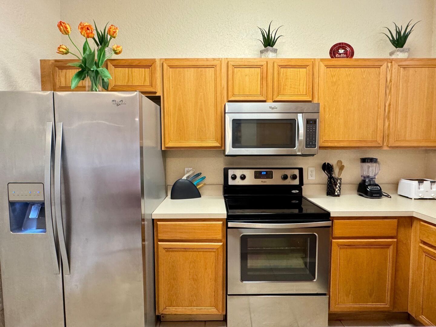 Una cocina con un refrigerador de acero inoxidable, un microondas, un horno y una cafetera.