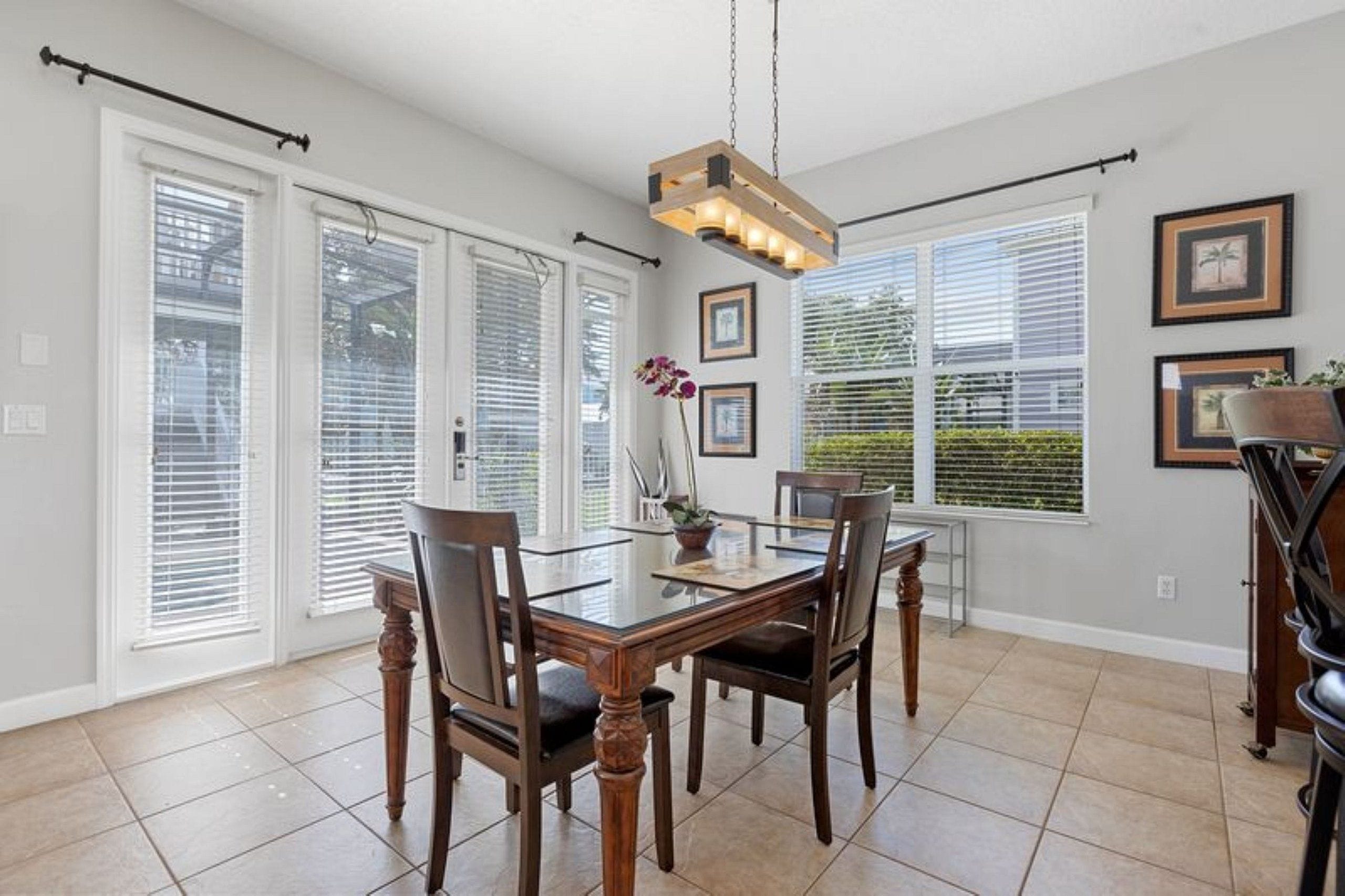 A dining area with a glass table, wooden chairs, and a pendant light.