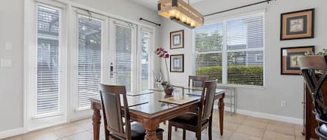 A dining area with a glass table, wooden chairs, and a pendant light.