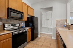 A kitchen with wooden cabinets, a black refrigerator, a stainless steel oven, and a microwave. - 4BR Reunion Resort Villa, Pool, Near Disney (Kissimmee)
