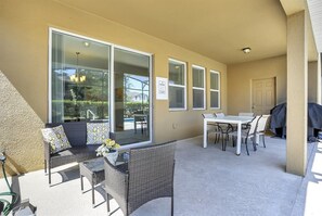 A covered patio area with outdoor furniture, including a sofa and a dining table with chairs. - Solterra 7BR Home Pool & Spa Near Disney (Davenport)