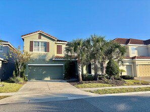 A two-story house with a garage, a driveway, and a well-maintained lawn. - 7BR Solterra Home, Pool & spa Near Disney (Davenport)