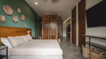 Un dormitorio con cama, cabecera de madera, televisor montado en la pared y armario.