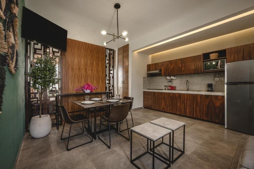 Una cocina moderna con armarios de madera, un refrigerador de acero inoxidable y un comedor con mesa y sillas.