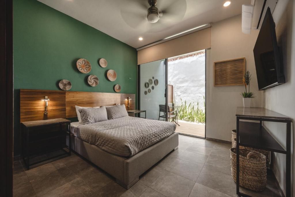 Un dormitorio moderno con cama, mesitas de noche, televisor y puerta corrediza de vidrio que da a un balcón.