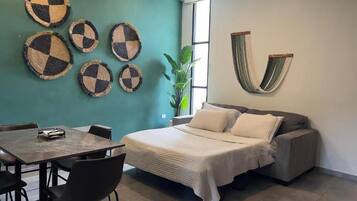 Una habitación con cama, una mesa, sillas y adornos en la pared.