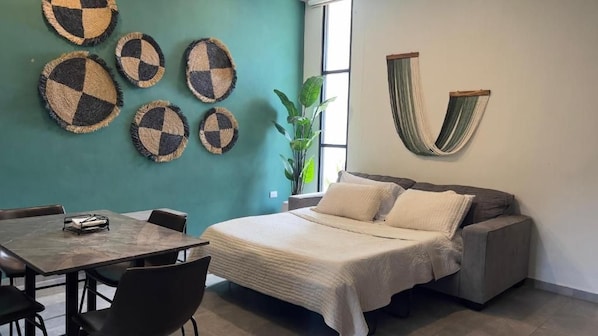 A room with a bed, a table, chairs, and wall decorations.