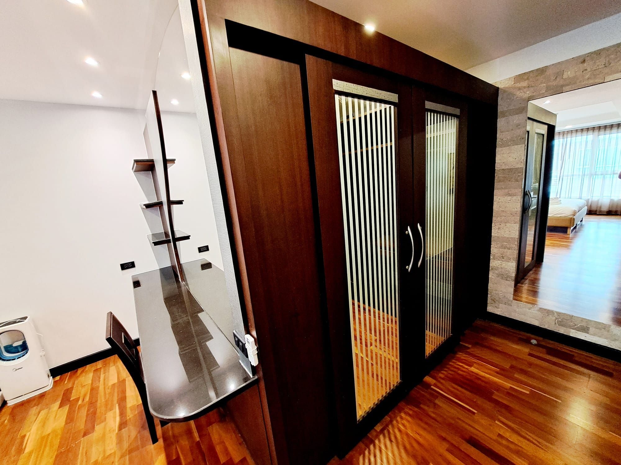 A modern interior with a wooden floor, a sliding door with vertical blinds, and a built-in shelf unit.
