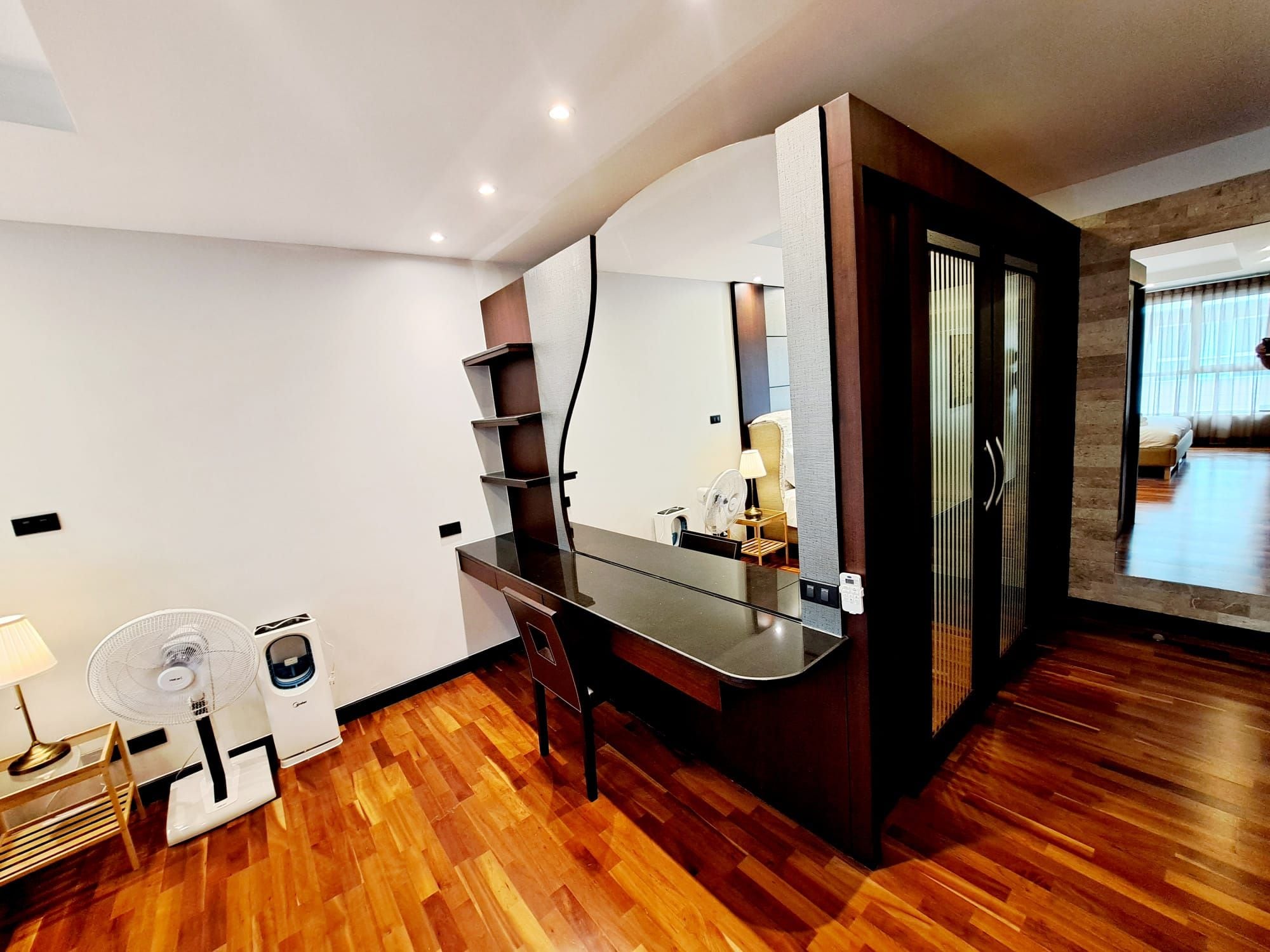 Une chambre d’hôtel moderne avec un plancher en bois, un grand miroir, un bureau et un lit.
