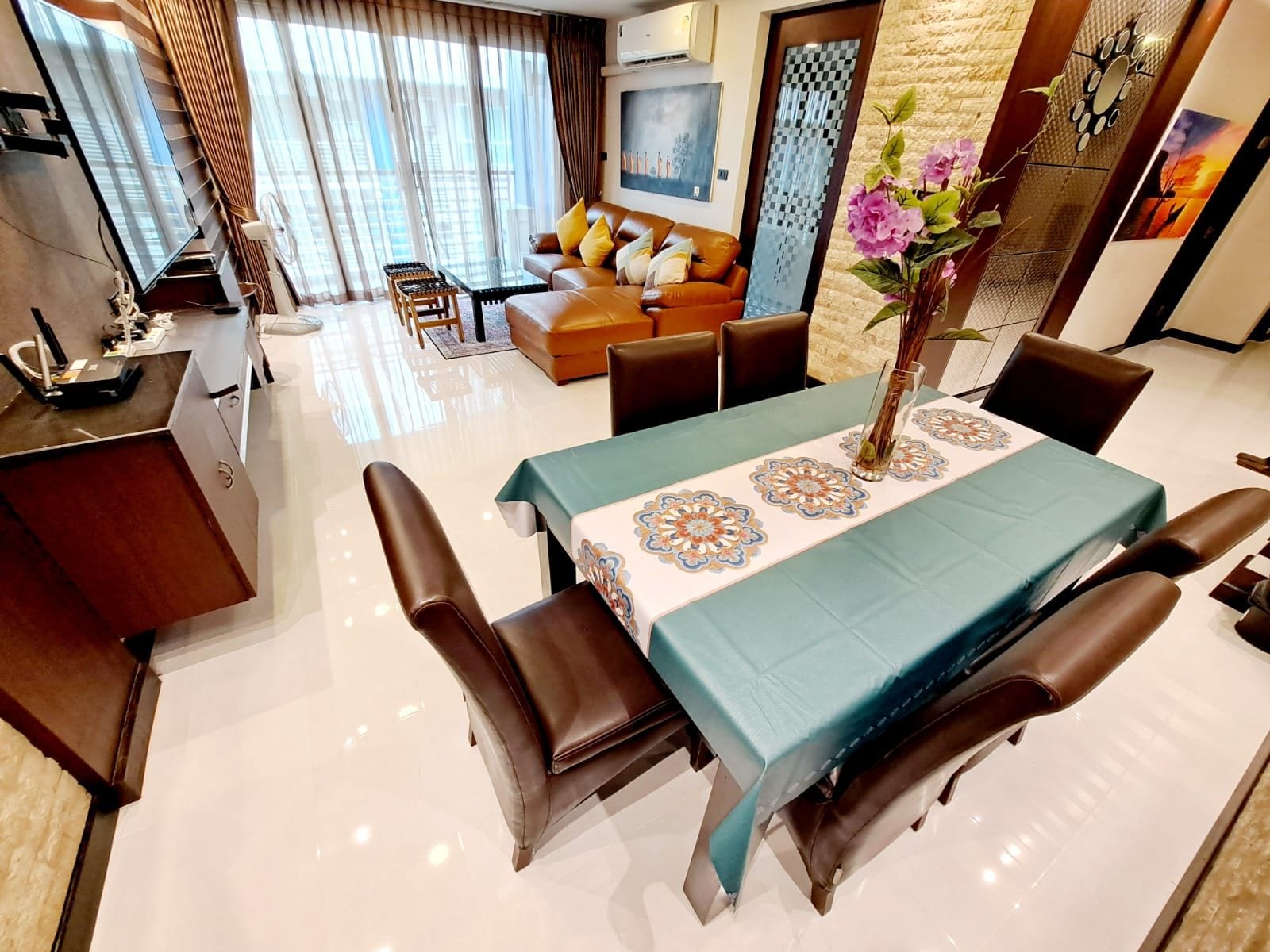 A modern living room with a dining area, featuring a sofa set, a coffee table, and a dining table with chairs.